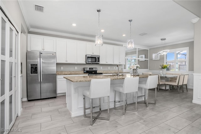 kitchen with white cabinetry, a kitchen island with sink, stainless steel appliances, and light stone counters