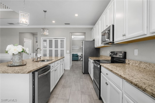 kitchen with light stone countertops, white cabinetry, sink, stainless steel appliances, and an island with sink