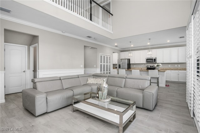 living room featuring crown molding and a high ceiling