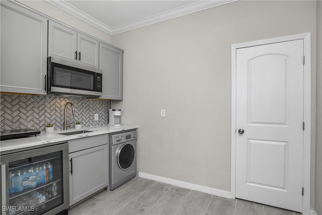 kitchen with sink, beverage cooler, washer / clothes dryer, crown molding, and gray cabinets