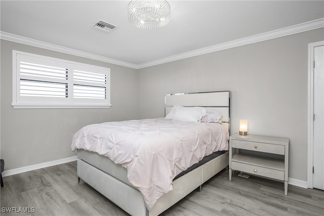 bedroom featuring light wood-type flooring, crown molding, and a notable chandelier