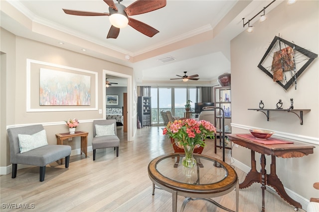 sitting room with rail lighting, light hardwood / wood-style floors, ornamental molding, and a tray ceiling