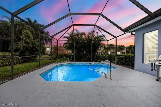 pool at dusk featuring glass enclosure and a patio area