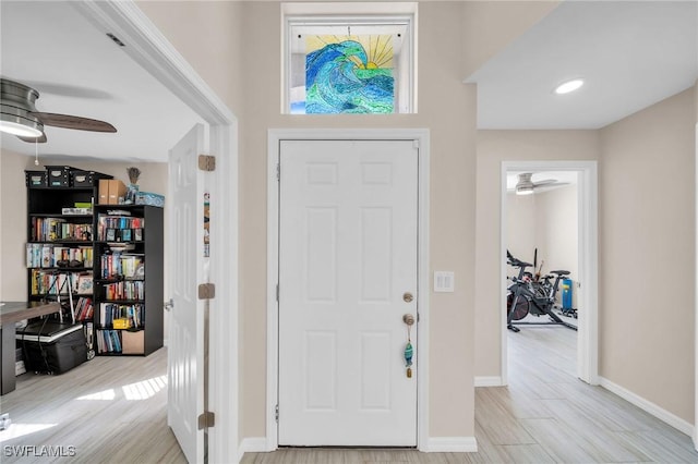 foyer with a ceiling fan, light wood-style flooring, and baseboards