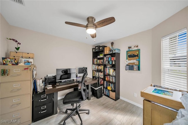 office with baseboards, visible vents, a ceiling fan, and light wood-style floors