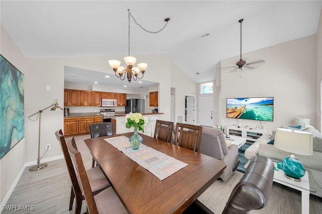 dining area featuring high vaulted ceiling, light wood-type flooring, and ceiling fan with notable chandelier