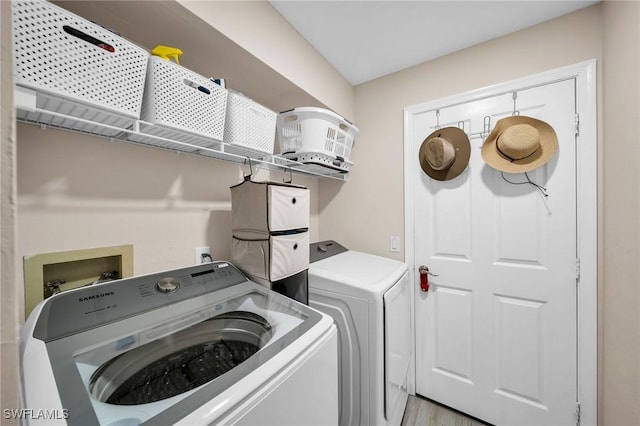 washroom with light wood-type flooring, separate washer and dryer, and laundry area