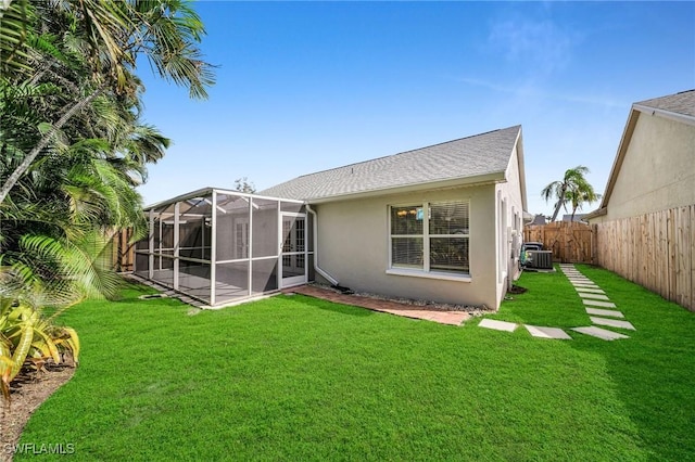 back of property with a shingled roof, central air condition unit, stucco siding, a yard, and a fenced backyard