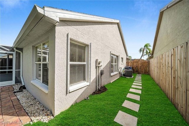 view of home's exterior featuring a yard, central AC, stucco siding, and a fenced backyard