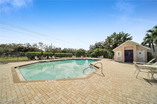 community pool with fence and a patio area
