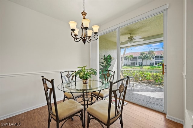 dining space with hardwood / wood-style flooring and ceiling fan with notable chandelier