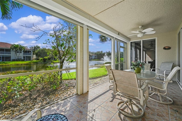 sunroom / solarium with a water view and ceiling fan