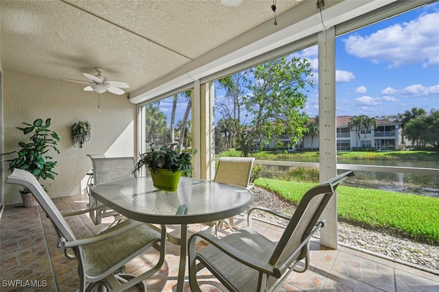 sunroom / solarium featuring ceiling fan and a water view