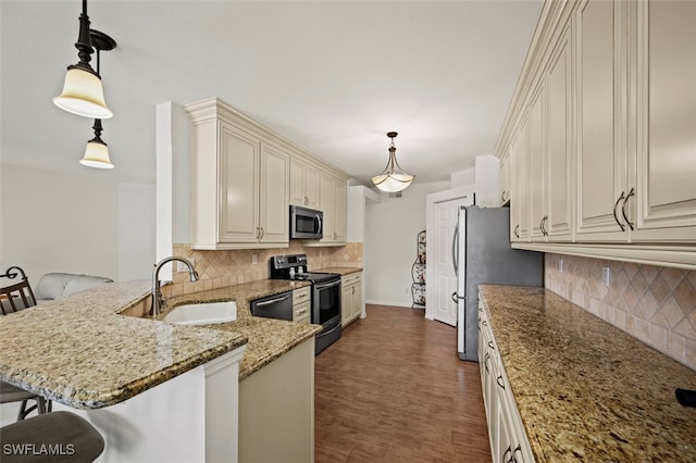 kitchen with kitchen peninsula, stainless steel appliances, decorative light fixtures, sink, and a kitchen bar