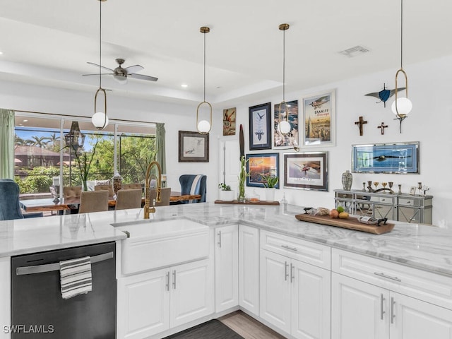 kitchen featuring sink, light stone countertops, pendant lighting, stainless steel dishwasher, and white cabinets