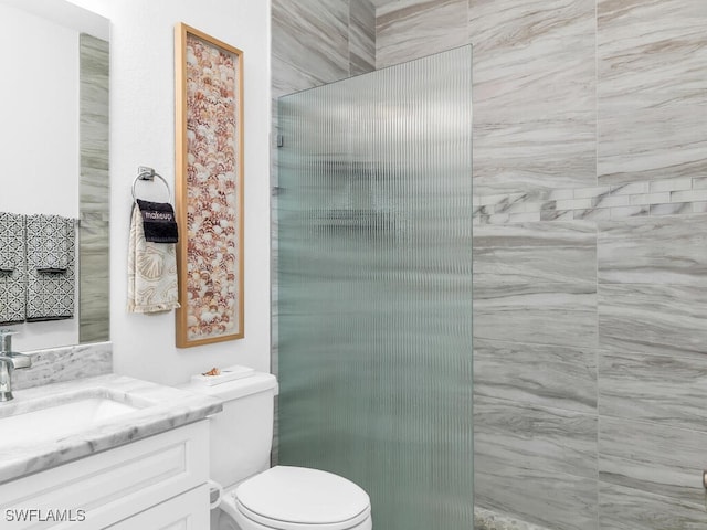 bathroom with vanity, toilet, and tiled shower