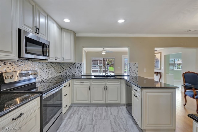 kitchen featuring sink, backsplash, appliances with stainless steel finishes, and kitchen peninsula