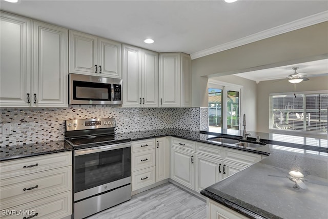 kitchen with stainless steel appliances, a sink, decorative backsplash, dark stone counters, and crown molding