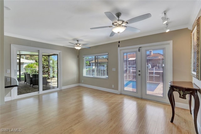 doorway to outside featuring light wood finished floors, baseboards, a ceiling fan, crown molding, and french doors