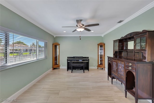 living area featuring visible vents, a ceiling fan, baseboards, light wood finished floors, and crown molding