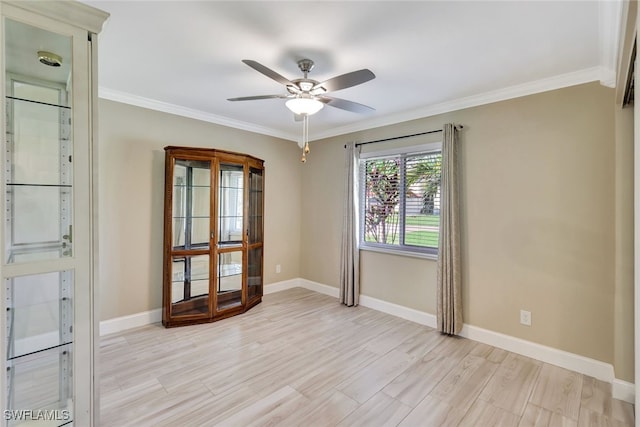 empty room with ornamental molding, light wood-style floors, and baseboards