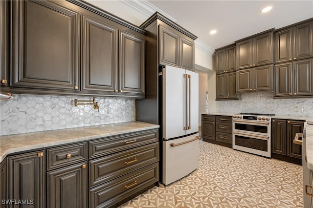 kitchen featuring range with two ovens, backsplash, dark brown cabinets, crown molding, and white refrigerator