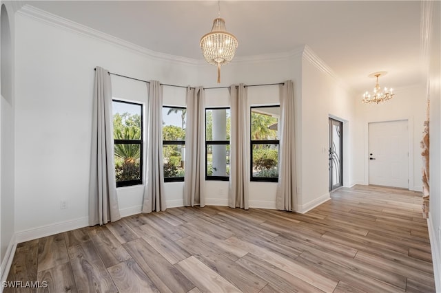 spare room featuring ornamental molding, light hardwood / wood-style flooring, and a chandelier