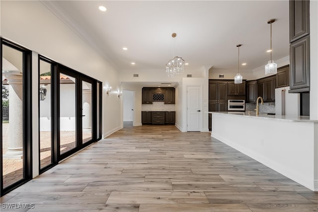 kitchen featuring light hardwood / wood-style flooring, oven, dark brown cabinetry, and decorative backsplash