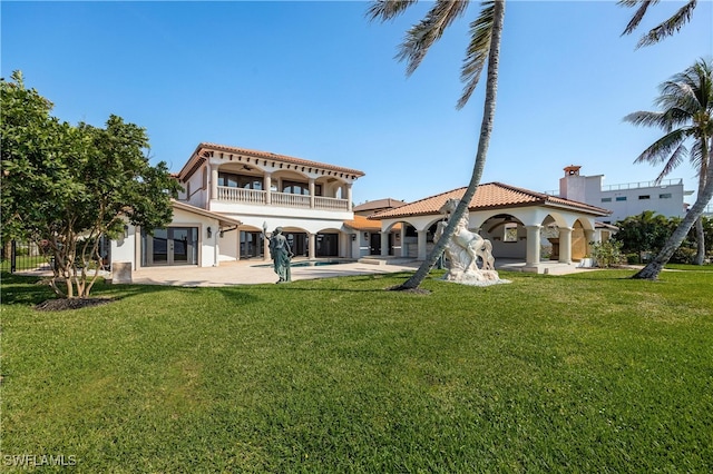 rear view of house with a patio area, a yard, and a balcony