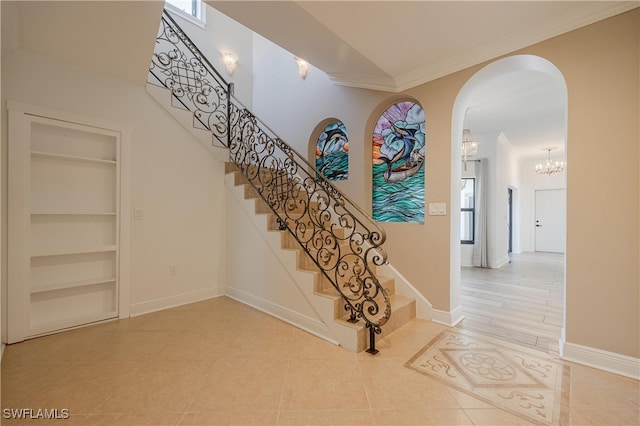 stairway featuring an inviting chandelier, crown molding, tile patterned floors, and built in shelves