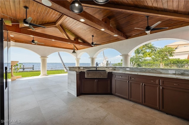 view of patio / terrace with a water view, ceiling fan, sink, and an outdoor kitchen