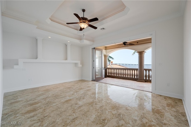 empty room featuring ornamental molding, decorative columns, ceiling fan, and a raised ceiling