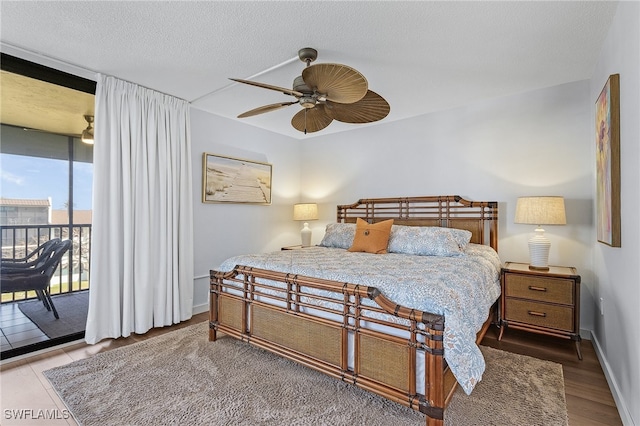 bedroom with hardwood / wood-style floors, access to outside, expansive windows, ceiling fan, and a textured ceiling