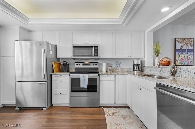 kitchen with a raised ceiling, white cabinetry, stainless steel appliances, and dark wood-type flooring