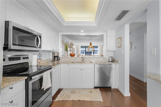 kitchen featuring white cabinets, sink, appliances with stainless steel finishes, decorative light fixtures, and light hardwood / wood-style floors