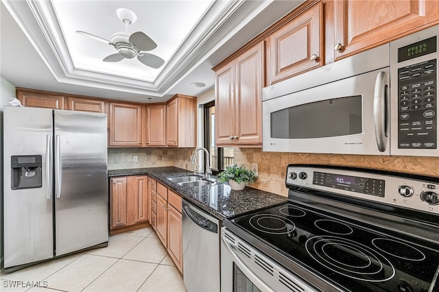 kitchen with appliances with stainless steel finishes, sink, a raised ceiling, light tile patterned floors, and crown molding