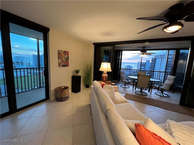 tiled living room with ceiling fan and a wall of windows