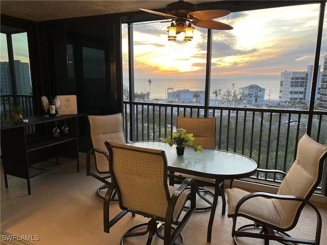 sunroom / solarium with ceiling fan and a water view