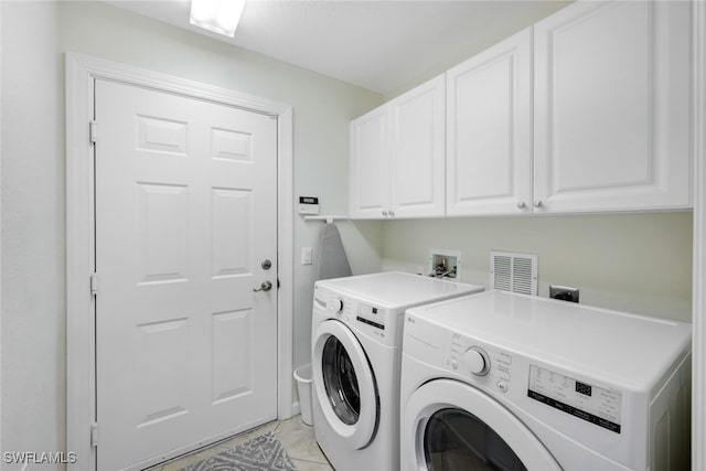 laundry room featuring washing machine and clothes dryer, light tile patterned floors, and cabinets