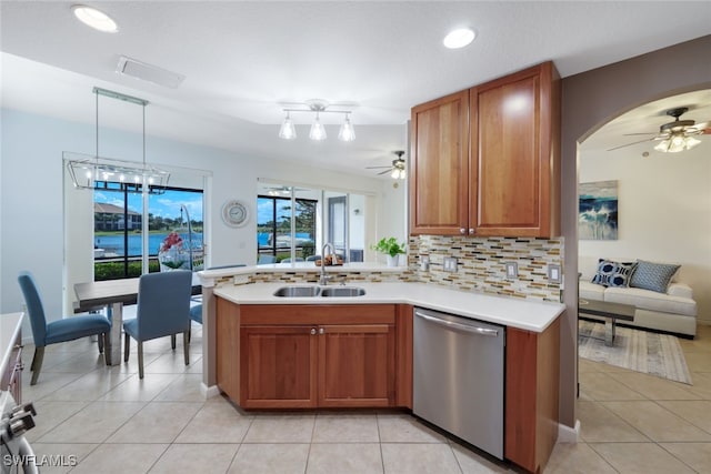 kitchen featuring decorative backsplash, dishwasher, ceiling fan with notable chandelier, pendant lighting, and sink