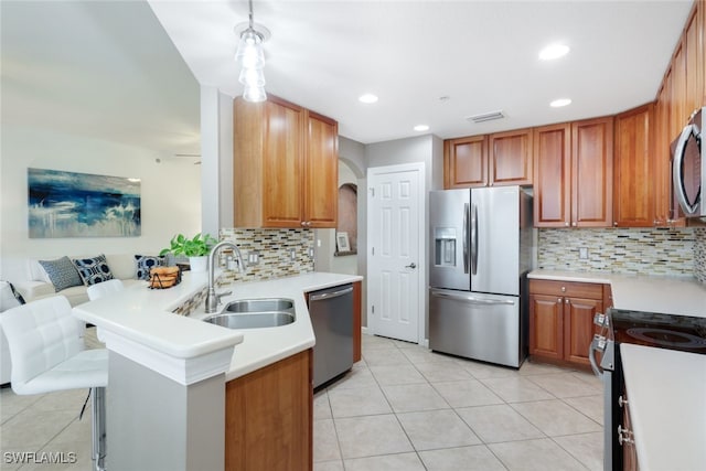 kitchen with appliances with stainless steel finishes, sink, decorative backsplash, and a kitchen breakfast bar