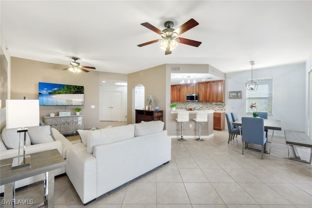 living room with ceiling fan with notable chandelier and light tile patterned floors