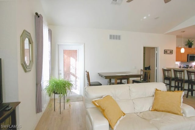 living room featuring ceiling fan, light wood-type flooring, and vaulted ceiling