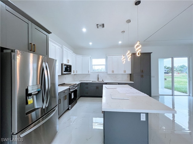 kitchen featuring appliances with stainless steel finishes, a center island, plenty of natural light, and white cabinets