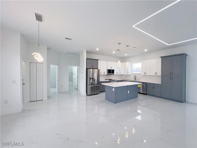 kitchen with decorative backsplash, stainless steel appliances, a center island, decorative light fixtures, and white cabinets