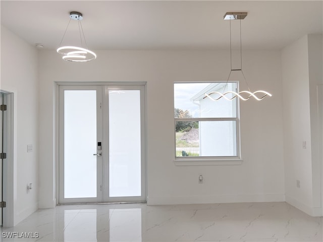 unfurnished dining area featuring french doors and an inviting chandelier