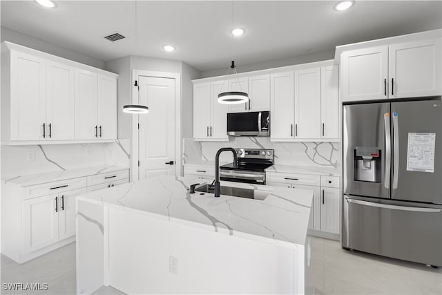 kitchen with stainless steel appliances, a center island with sink, white cabinetry, light stone counters, and tasteful backsplash