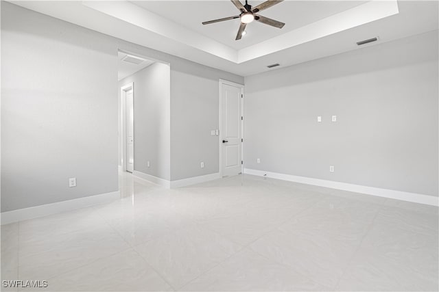 unfurnished room with ceiling fan and a raised ceiling