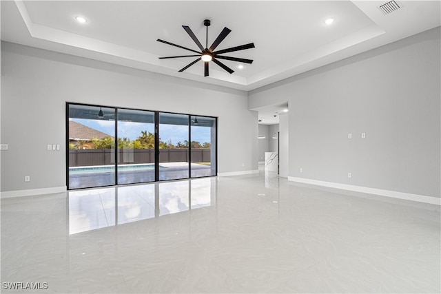 spare room with ceiling fan and a raised ceiling