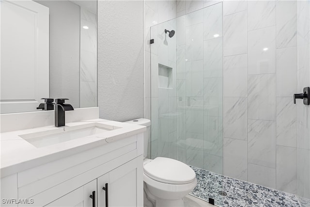 bathroom featuring toilet, vanity, and a tile shower